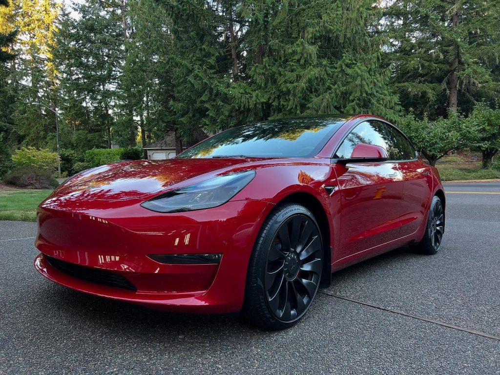 Red Tesla Model 3 with a high-gloss finish parked outdoors
